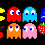 Personagens pixelados do jogo Pac-Man, incluindo Pac-Man, fantasmas coloridos e itens como cereja e morango, sobre fundo preto.